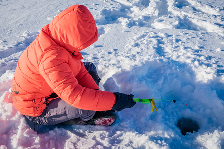 A girl on winter fishing is fishing on the lakeの写真素材