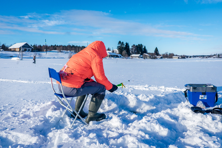 A girl on winter fishing is fishing on the lakeの写真素材