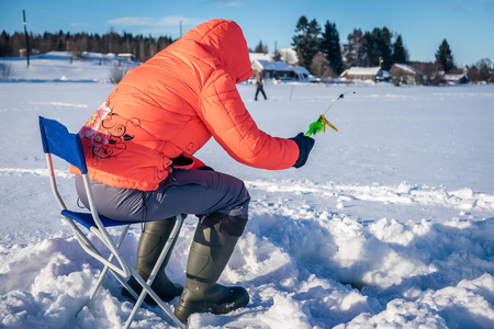A girl on winter fishing is fishing on the lakeの写真素材
