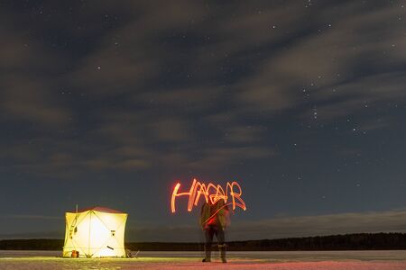 A tent for winter fishing at night stands on a lakeの写真素材