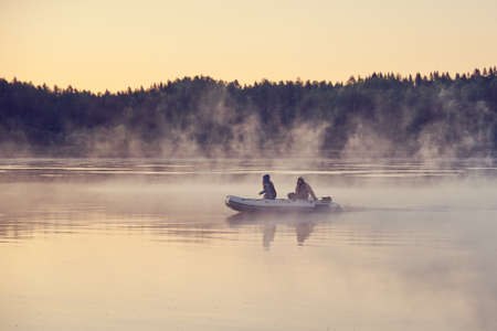 Fishermen on a boat in the morning fog.の写真素材