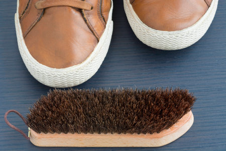 Cleaning a pair of brown leather shoes with a white border on a dark woodの写真素材