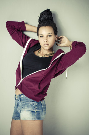 Young african girl with black dreadlocks wearing trendy hip-hop fashion and posing in front of a grey wall の写真素材
