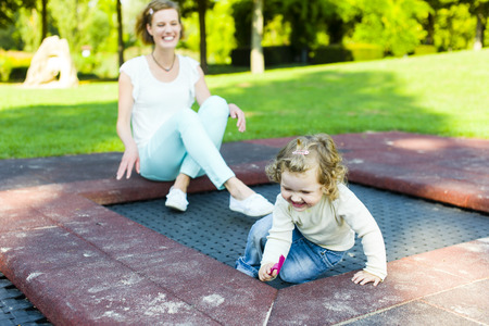 Mutter und Kleinkind zusammen auf dem Spielplatz draussen.の写真素材