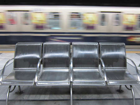 FOUR EMPTY CHAIRS WITH METRO UNDERGROUND RAIL ON THE BACKGROUND の写真素材