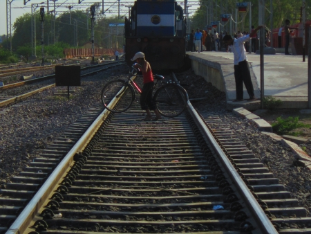 A MAN CROSSING RAILINE IN FRONT OF TRAIN ENGINE の写真素材