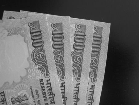 CLOSE UP OF HUNDRED RUPEE NOTES ON BLACK BACKGROUND DEPICTS BLACK MONEY.の写真素材