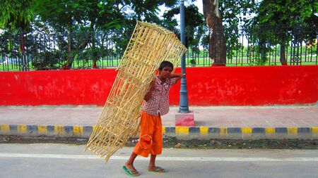 BOY CARRYING BAMBOO FURNITURE.  SHOT AT GANDHI MAIDAN, PATNA, BIHAR, INDIA AFTERNOON HOURS , 23 AUGUST 2012のeditorial素材