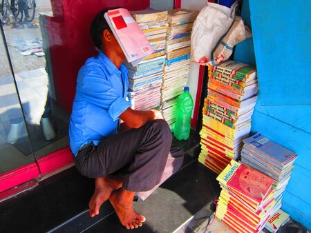 BOOK SELLER SLEEPING WITH BOOK COVERING HIS FACE. SHOT AT GANDHI MAIDAN, PATNA, BIHAR, INDIA, ASIA DURING AFTERNOON HOURS ON 29.08.12のeditorial素材