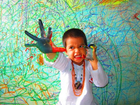 HAPPY KID PLAYING WITH COLOUR WITH COLORED FINGERS IN COLORFUL WALLの写真素材
