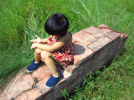 GIRL SITTING ON ARCHITECTURAL REMAINS AT KUMRAHARの写真素材