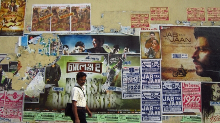 MAN WALKING PAST CINEMA POSTER.SHOT AT CALCUTTA INDIA: MORNING HOURS ON NOVEMBER 12,2012.
