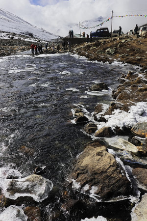 frozen mountain stream flowing through the scenic alpine valley at yumesodong or zero point, the beautiful himalayan valley located in north sikkim, indiaの写真素材