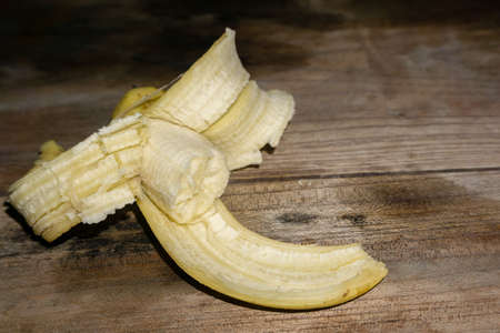 An isolated shot of a half eaten banana with peel spread on a table top.の写真素材