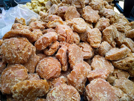 A close up shot of a bowl of Jaggery. It is a concentrated product of cane juice & often date or palm sap without separation of molasses & crystals & can vary from golden brown to dark brown in colourの写真素材