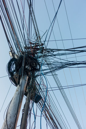 Electricity poles with overcrowded wires and distribution box in India.
