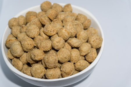 A close up shot of soya bean nuggets in a bowl with white background. Soya nuggets are a rich source...