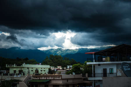 31st july 2021. Dehradun, Uttarakhand, India. A wide angle view of mussoorie hills from dehradun city with dark clouds and sun.のeditorial素材