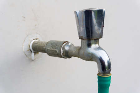 A closeup shot of a metallic tap with a green pipe on the nozzle. Uttarakhand India.