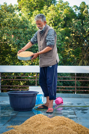 Dehradun City Uttarakhand India. March 21st 2022. Indian Man processing wheat post harvest. Wetting and Drying process.のeditorial素材