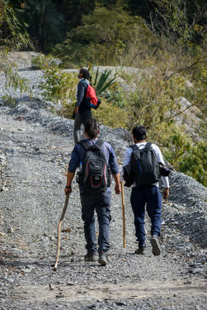 January 1st 2020 Uttarakhand INDIA. Hikers with backpacks and sticks ascending on a uphill trail.の写真素材