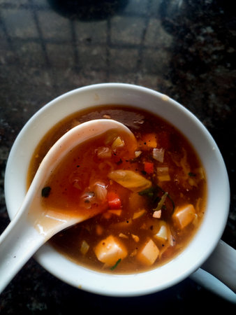 Home made Hot and sour mix vegetable soup in a white bowl with a spoon. Uttarakhand India.の写真素材