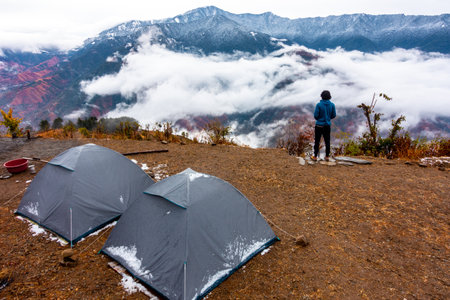 June 28th Nag tibba Uttarakhand India. A man enjoying a breathtaking view of snow capped mountain peaks in the Himalayas from a Campsite.の写真素材