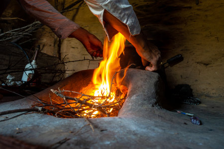 A burning clay stove fireplace inside a mud house in a rural village of Uttarakhand, India.