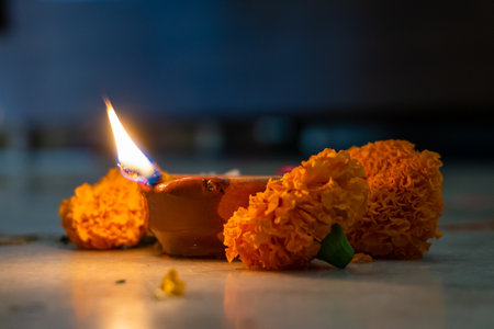 A burning mud lamp (diya) surrounded by vibrant flowers during Navratri, a Hindu festival honoring Indian goddesses. Captured in Uttarakhand, India.の写真素材