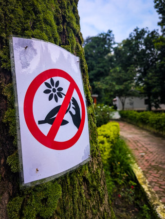 A sign on a tree prohibiting picking flowers in a park setting.の写真素材