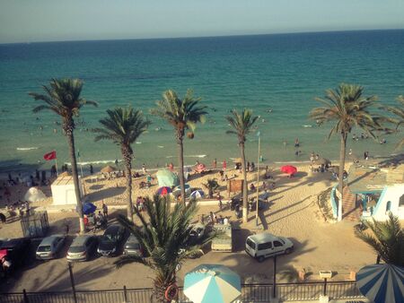 People relax at the resort enjoying the beach, sea views and palm trees.