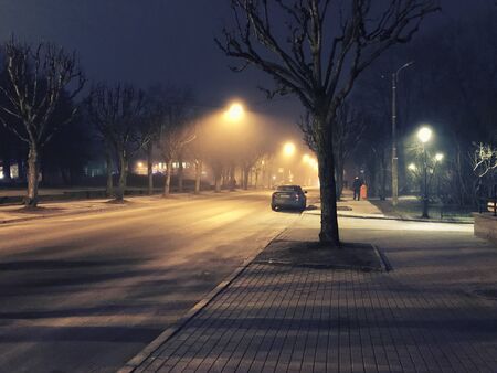 Fog enveloped the street of a deserted city at night.の写真素材
