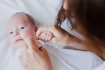 Mom playing with the baby holding his hand and smilingの写真素材