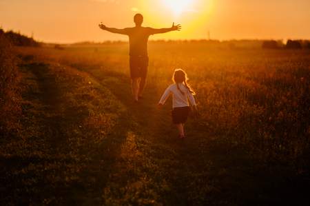 daughter running to father in the field at sunset,silhouetteの写真素材