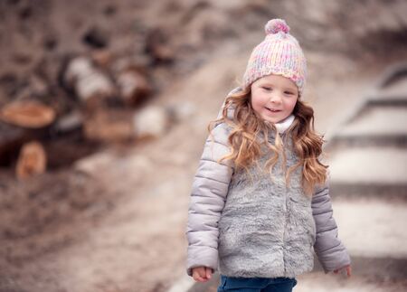 Child girl ,dressed in a warm coat stands and look away with a smile
