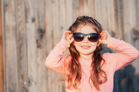 little girl outdoors wearing sunglasses, laughingの写真素材