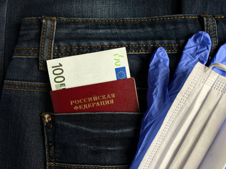 Russian passport and money, 100 euros are in the jeans pocket. Blue gloves and a mask are next to it.の写真素材