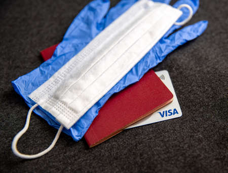 Mari El, Russia - May 10, 2021: Credit silver visa card in the document with blue glove and white mask. Dark gray backgroundのeditorial素材