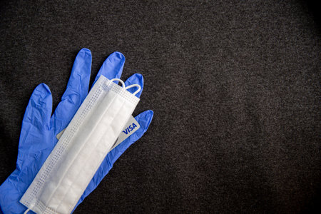 Mari El, Russia - May 10, 2021: Blue latex glove and white mask, visa plastic card. Dark textile backgroundのeditorial素材