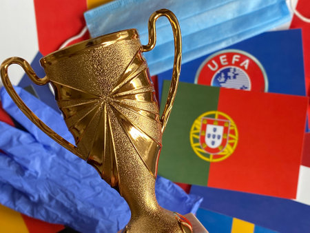Mari El, Russia - June 12, 2021: Mask and gloves, the winner's cup are on the background of the UEFA logo and Portugal, Portuguese flags. Euro 2020 competitions. Tourist trip. Championshipのeditorial素材