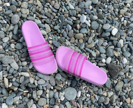 Bright pink slippers are on the pebble beach. Summer walk, sea tourism and travel. Flip-flopsの写真素材