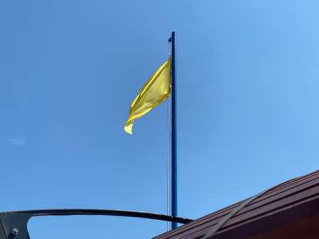 Yellow flag on the beach - indicates that a lifeguard is present. The roof is visible. Blue sky