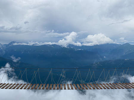 Rope bridge in the mountains at a height in the cloudsの写真素材