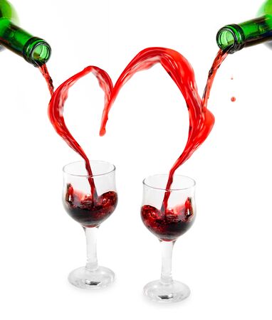 Heart from pouring red wine in goblets isolated on whiteの写真素材