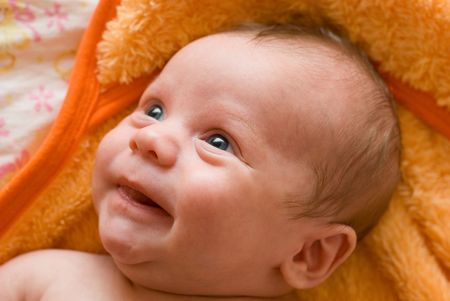 Portrait of laughing baby boy lying on the bedの写真素材