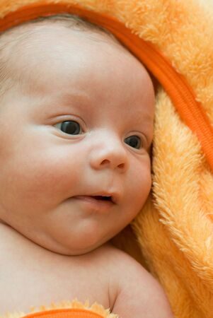 Closeup Portrait of baby boy lying on the orange blanketの写真素材