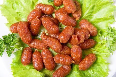 grilled sausages closeup on green lettuce with isolated on whiteの写真素材