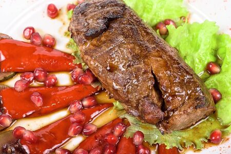 Roasted beef steak with pomegranate closeup at plateの写真素材