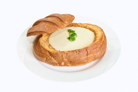 Cheese soup at baked bread as plate on a white backgroundの写真素材
