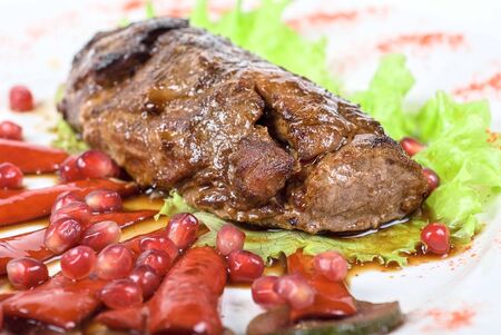 Roasted beef steak with pomegranate closeup at plateの写真素材